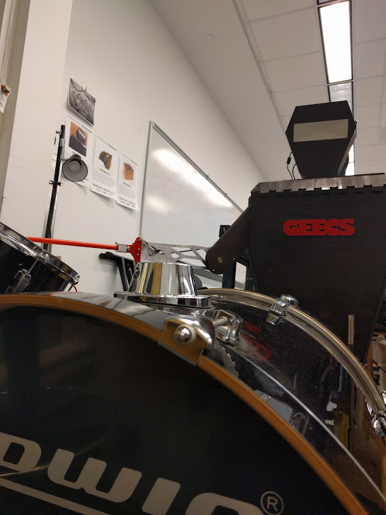 bass drum in foreground, black and red robotic drummer behind it