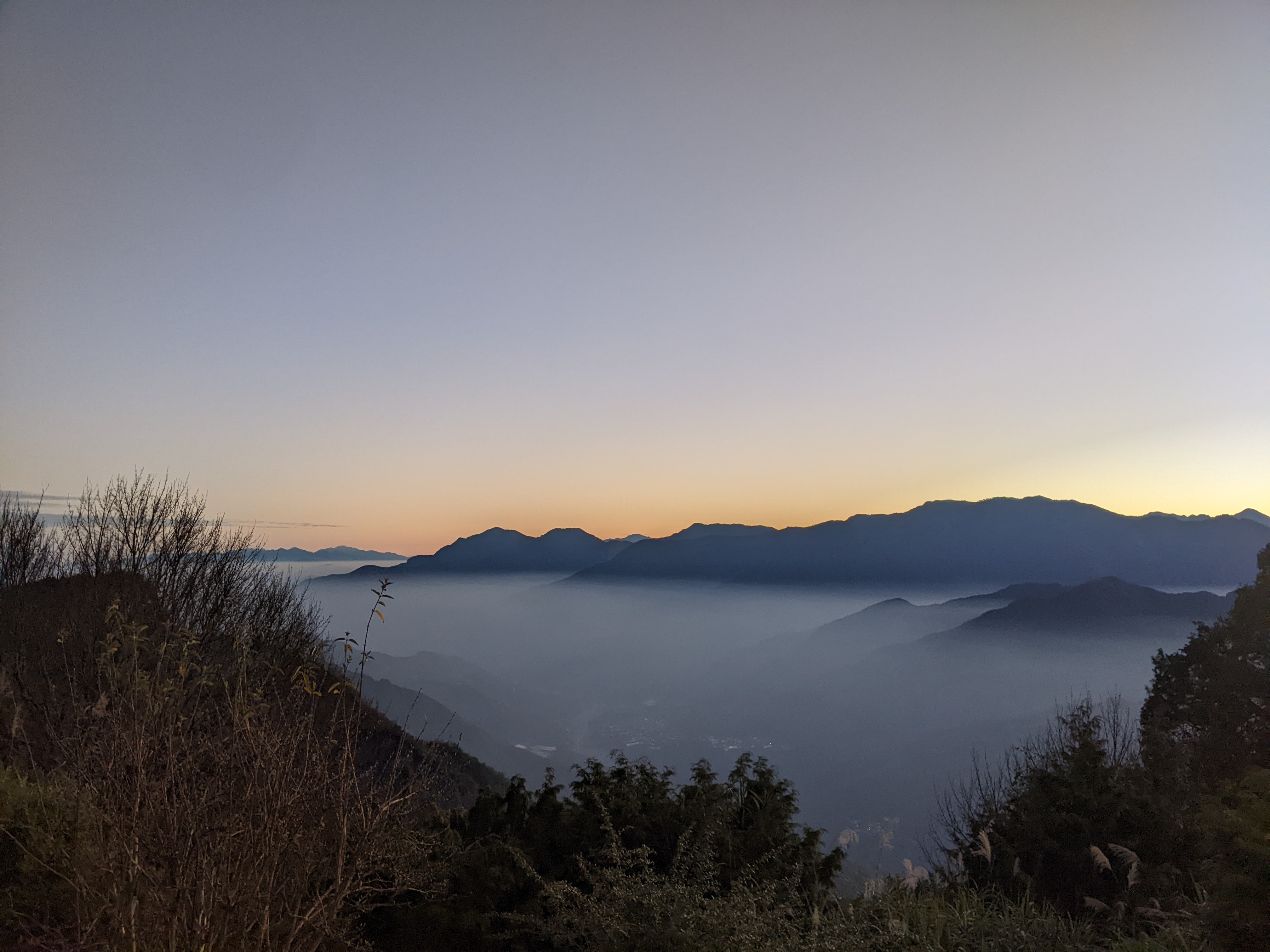 sunrising behind mountains, sky orange behind faded blue mountains