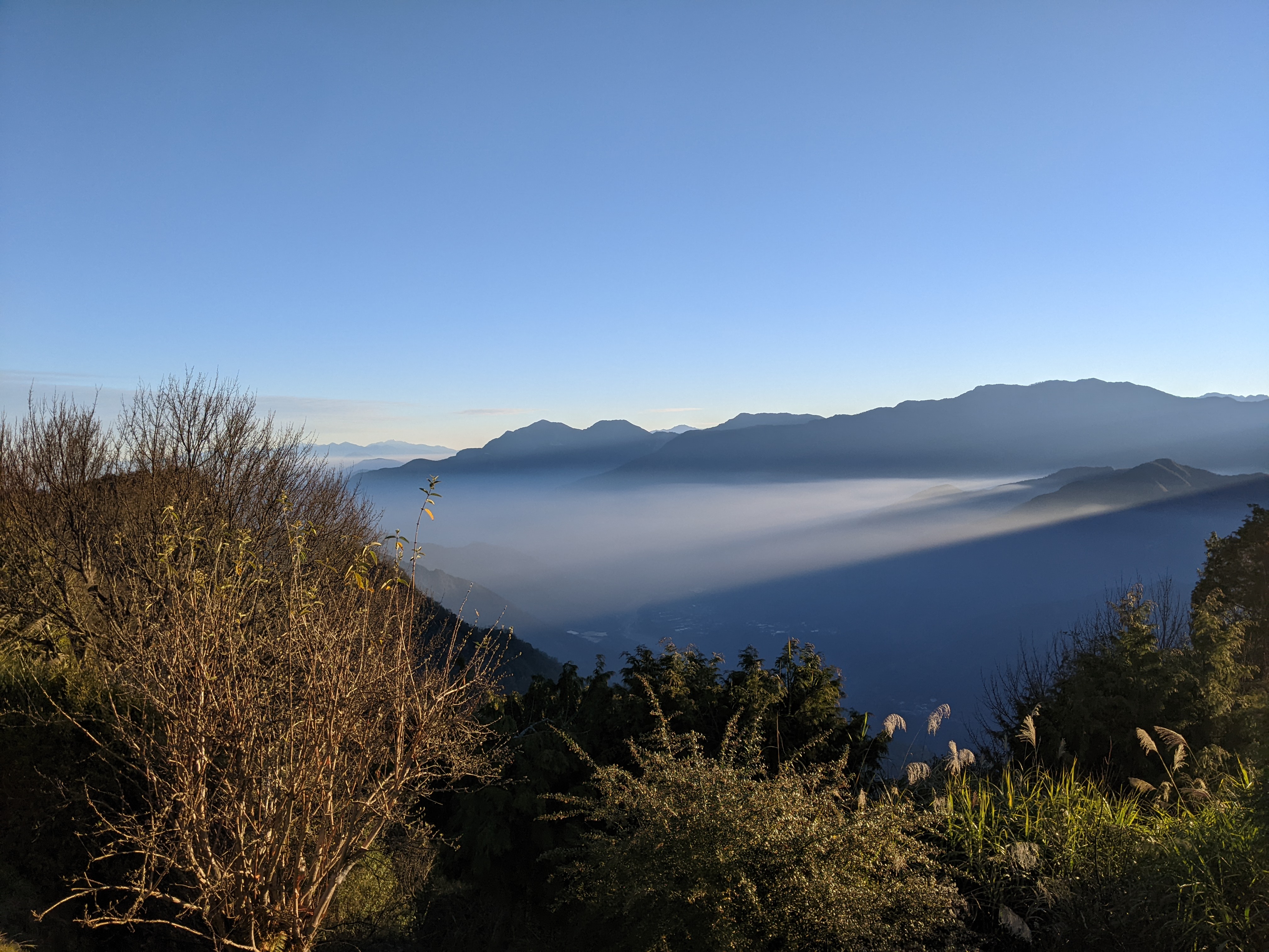 sunrising behind mountains, sky blue with sunrays coming from behind mountains