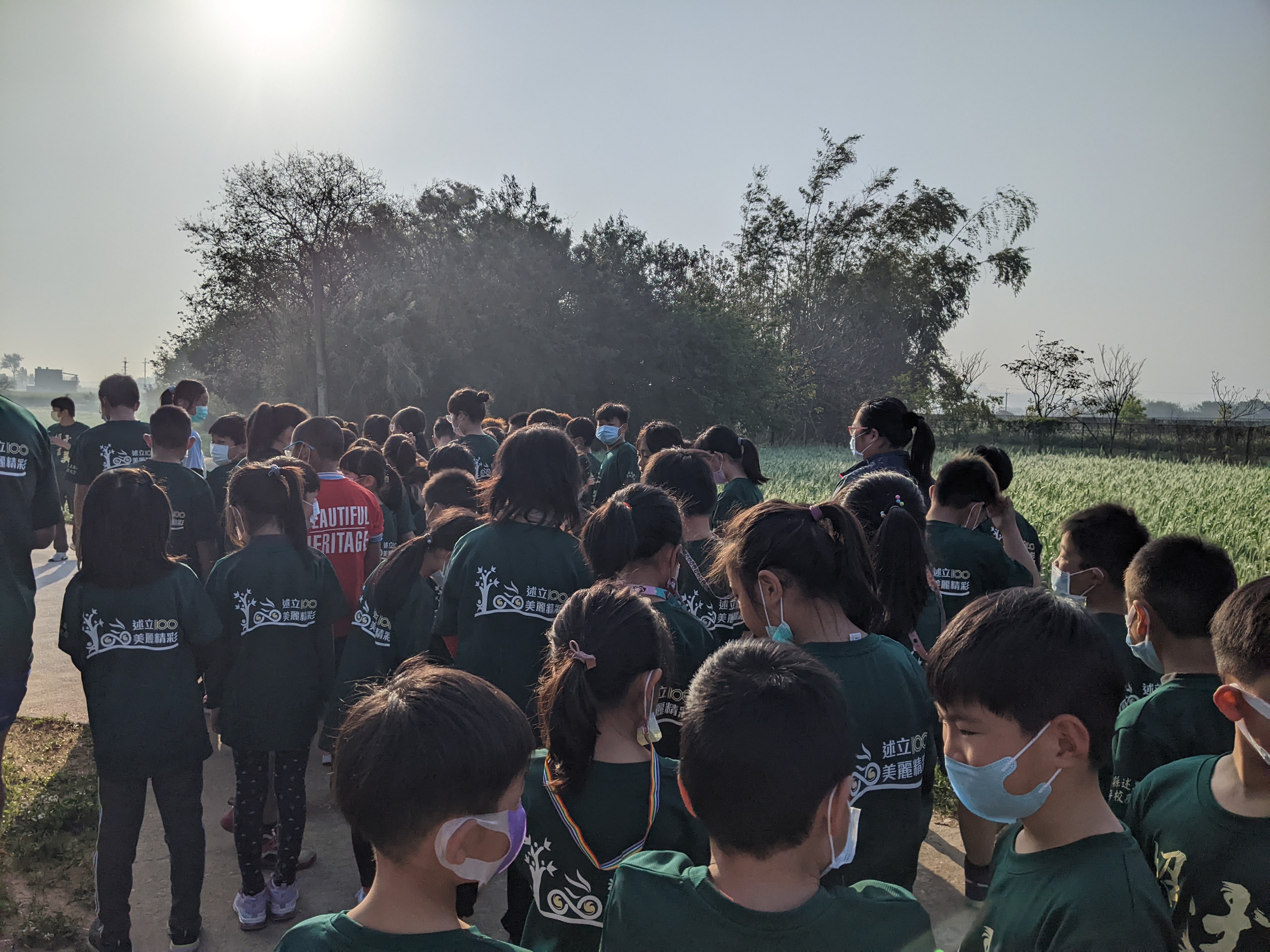 students in matching green school shirts standing in a clump in preperation for a run